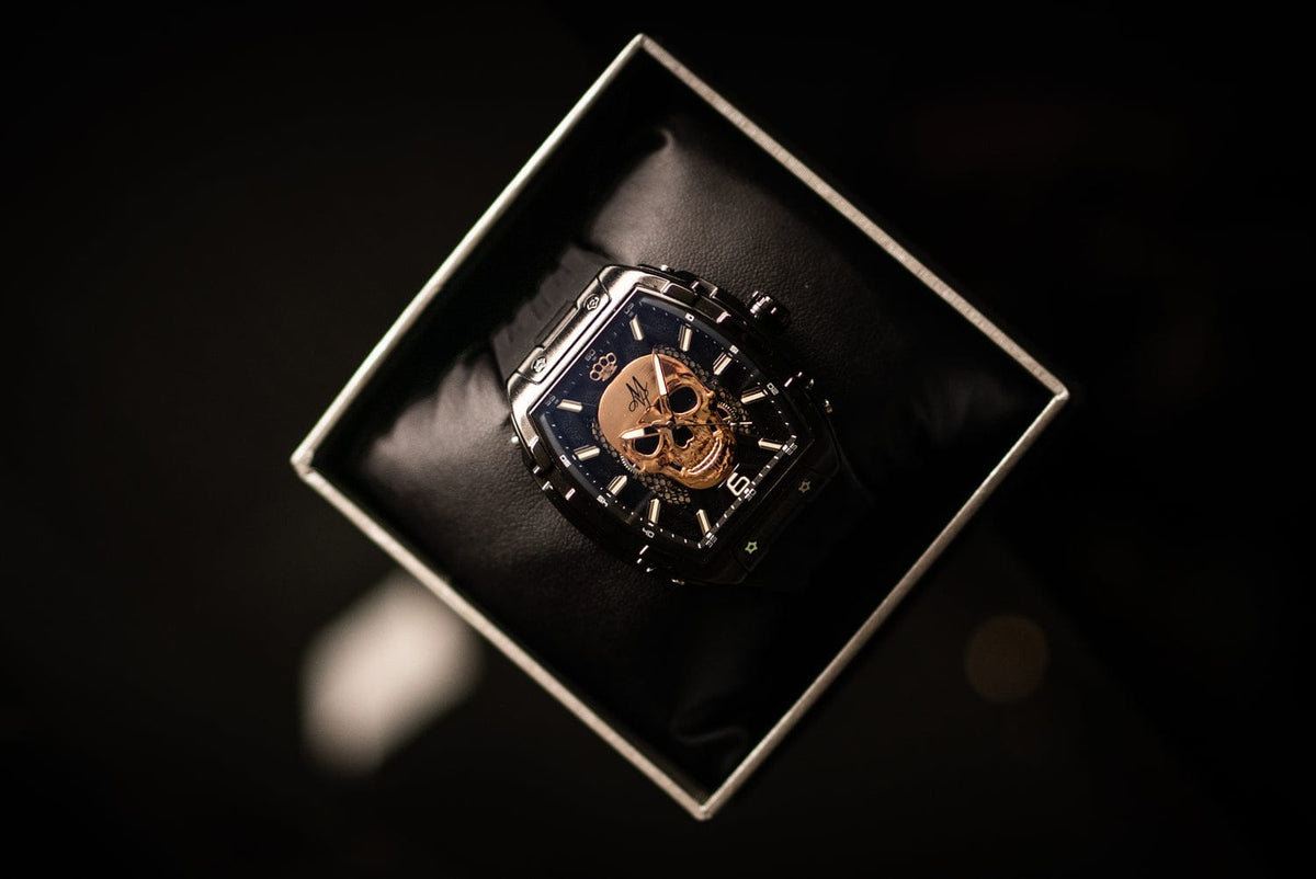 MVL Automatic Skull Watch in black in an open watch box, angled top view on a dark surface