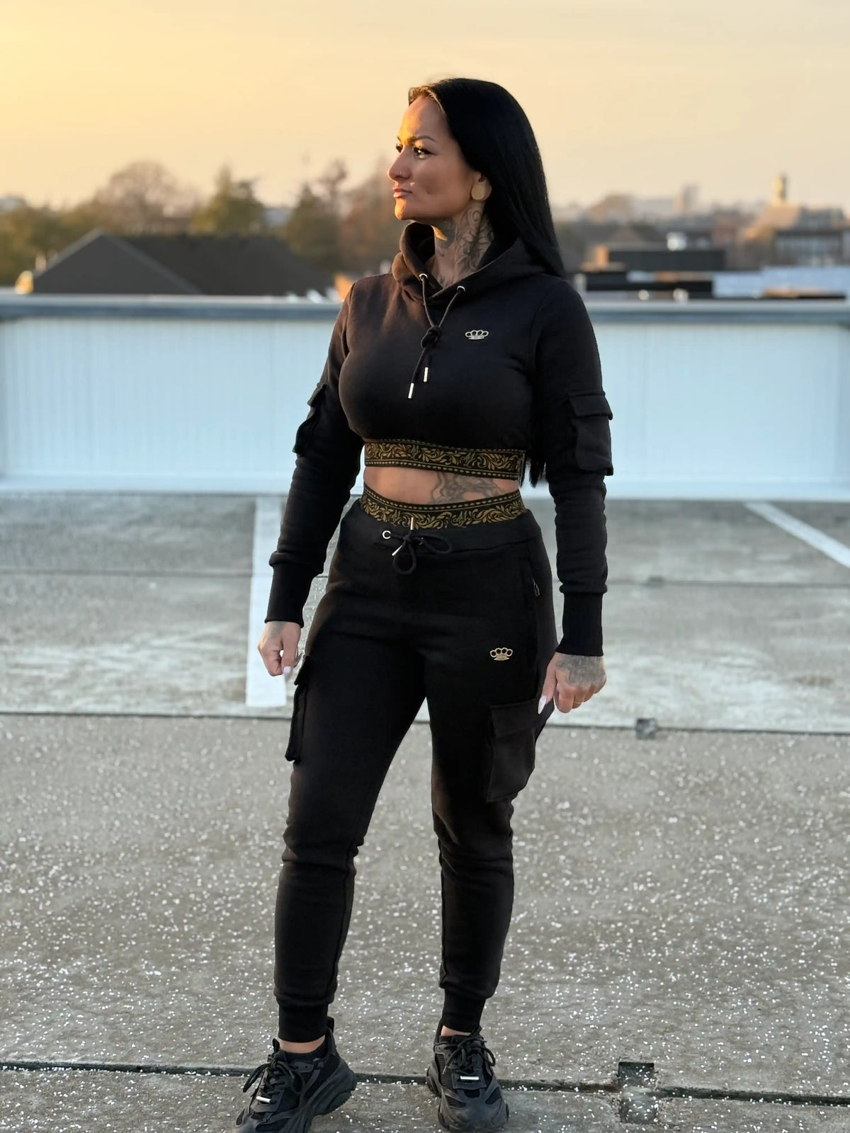 Model im MVL Meander Damen-Hoodie und Jogginghose auf einem Dach bei Sonnenuntergang