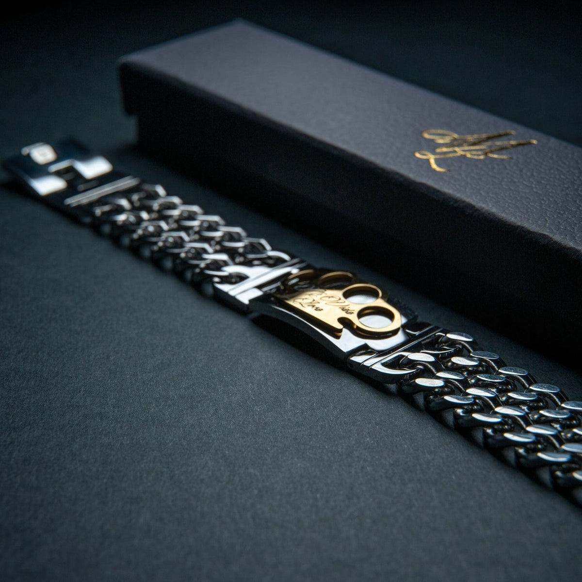 Bracciale Mi Vida Loca MVL argento con placca logo MVL dorata accanto alla confezione regalo nera