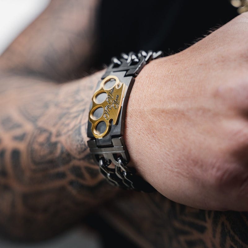 MVL Bracelet czarno-złota na nadgarstku wytatuowanej ręki, złote logo MVL w kadrze