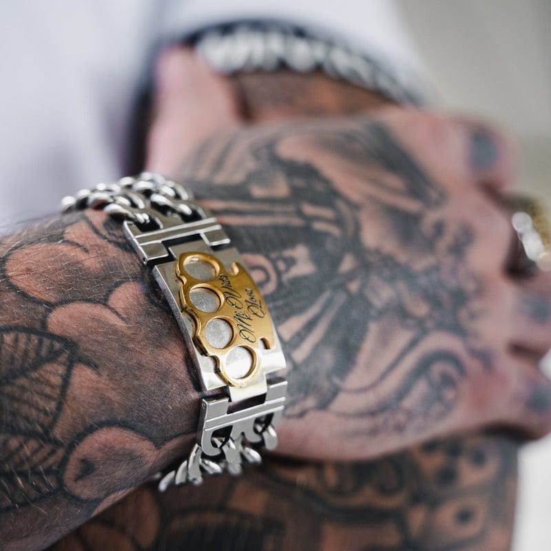 Bracciale MVL argento con logo MVL dorato al polso tatuato, primo piano